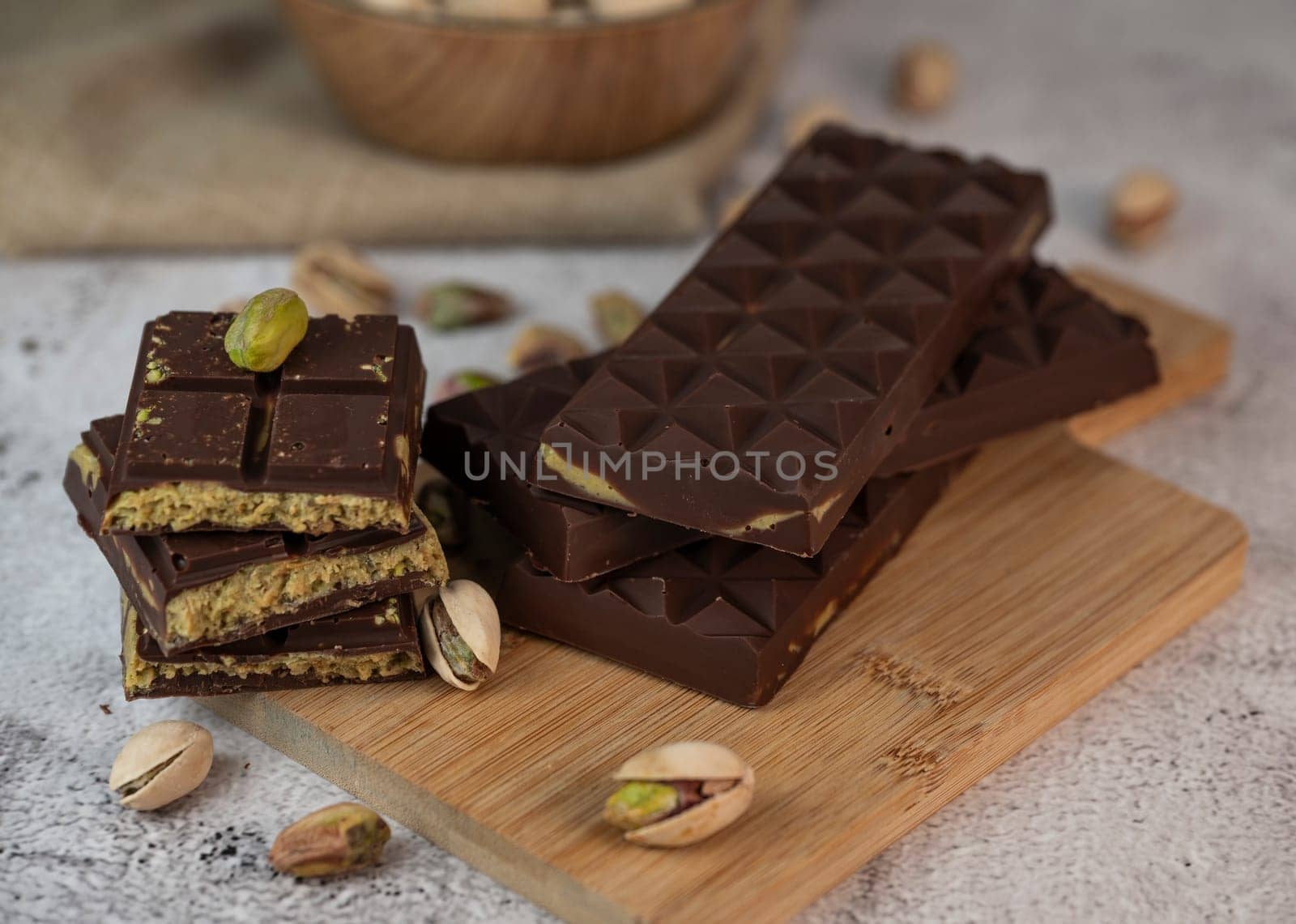 Gourmet chocolate mixed with crunchy kadaif pistachio pieces is beautifully presented on a wooden board, making a perfect treat in Dubai's culinary scene.
