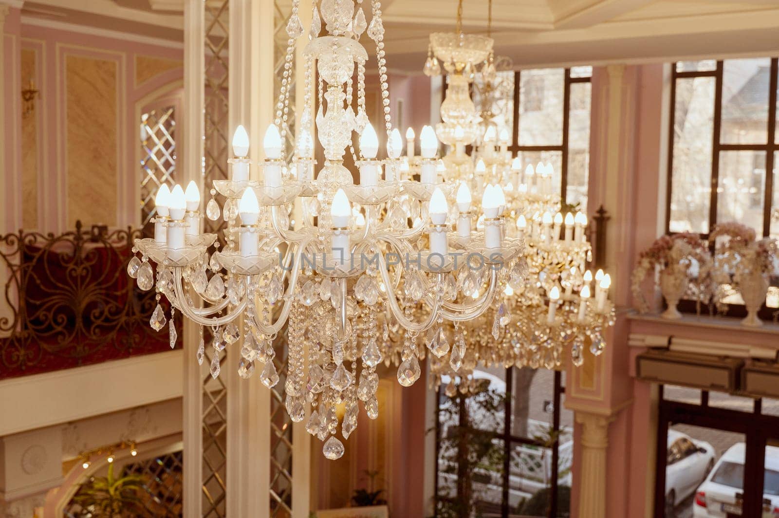 huge and luxurious chandelier on the ceiling in the hall. Elegant crystal chandelier with flame-shaped bulbs in a formal setting.