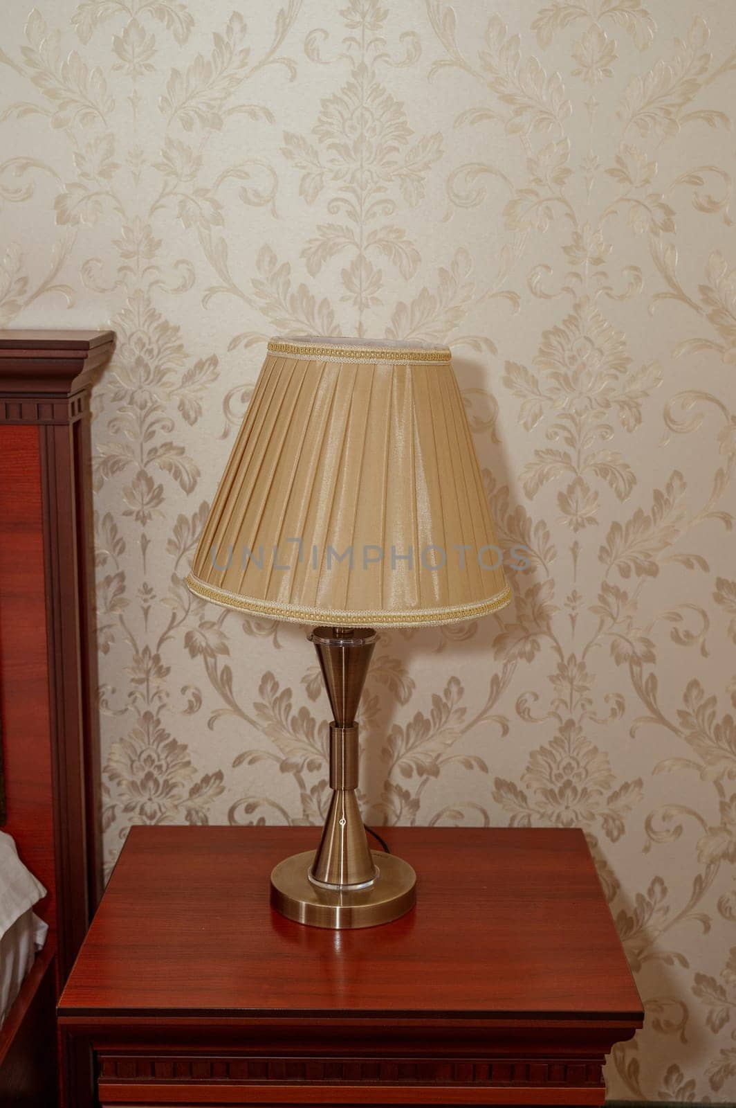 Table lamp with golden silk lampshade on wooden base. Red bedside table. High quality photo