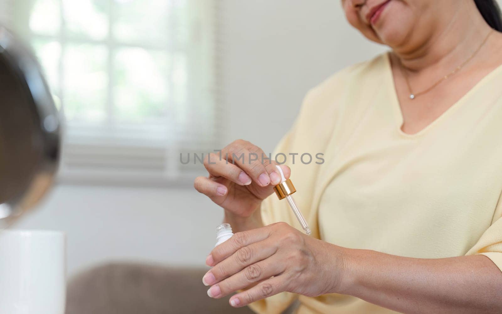 The elderly woman carefully applies serum, emphasizing the significance of skincare in her daily routine, highlighting beauty at any age.