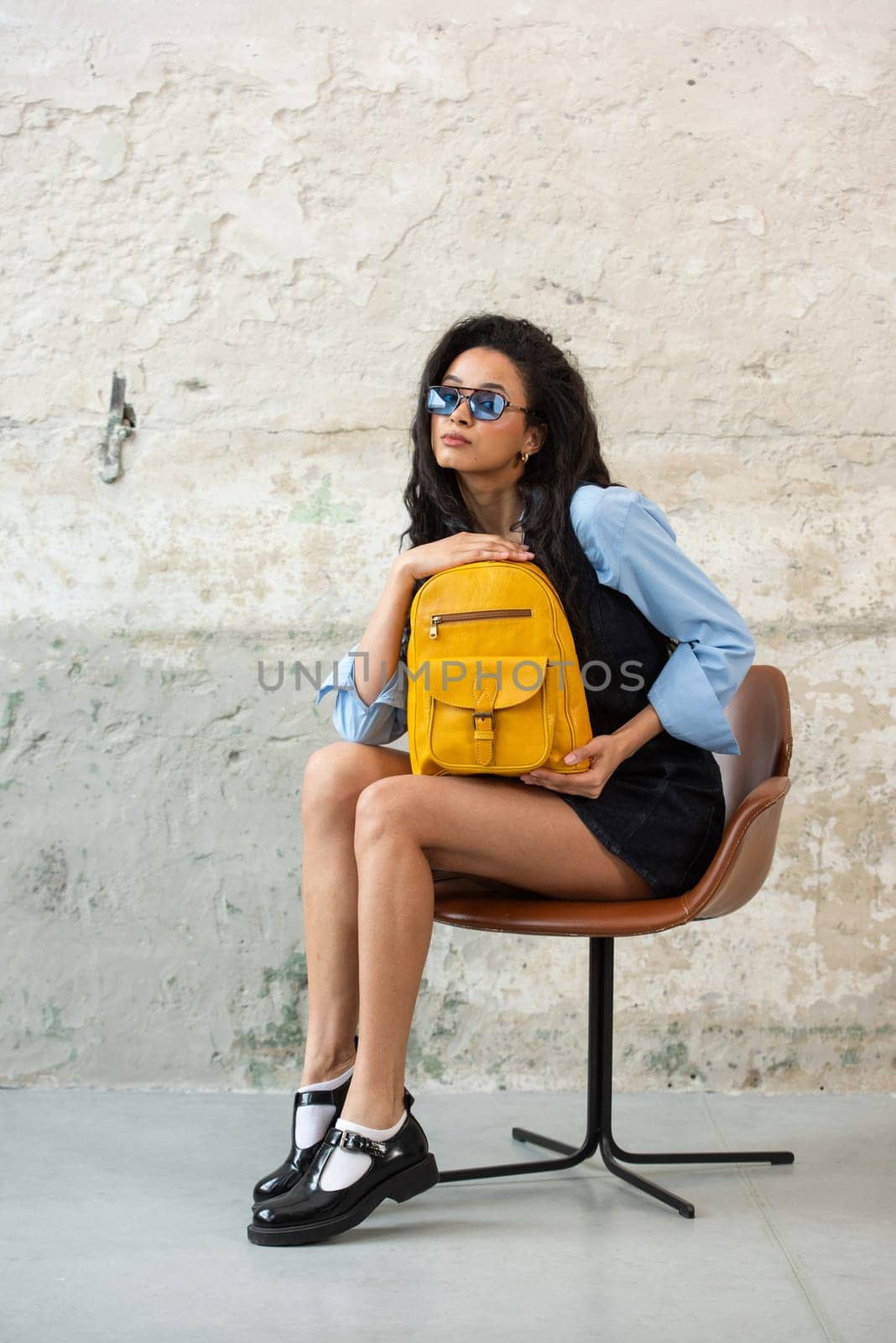 A fashionable model confidently showcasing a modern outfit while sporting a yellow backpack accessory