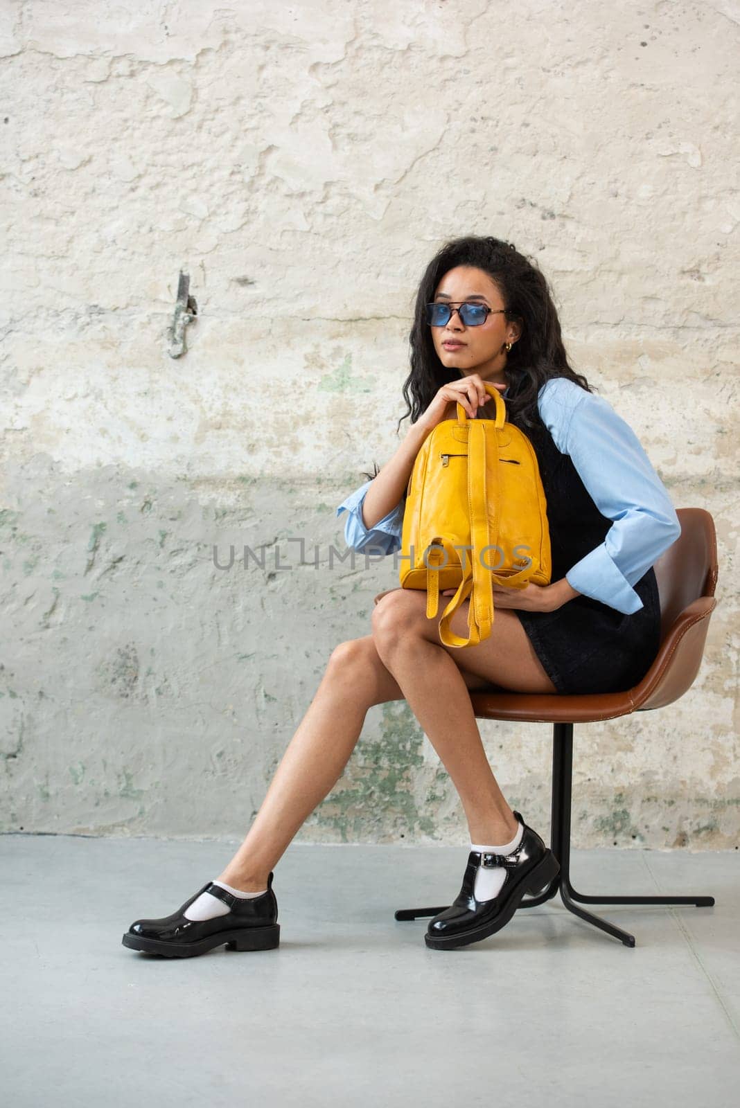 A fashionable model confidently showcasing a modern outfit while sporting a yellow backpack accessory