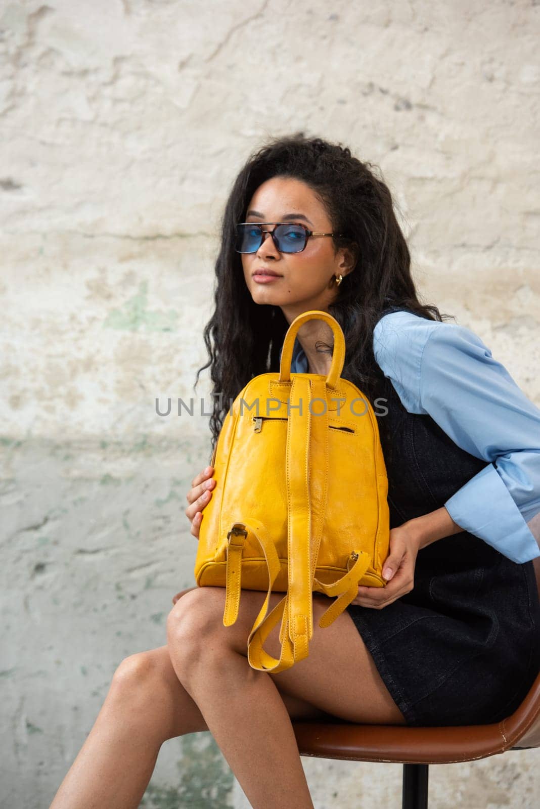 A fashionable model confidently showcasing a modern outfit while sporting a yellow backpack accessory