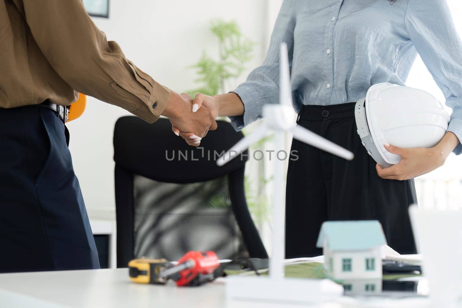 A handshake between two professionals signifies a partnership in their sustainable housing project, emphasizing collaboration and commitment to eco-friendly solutions.