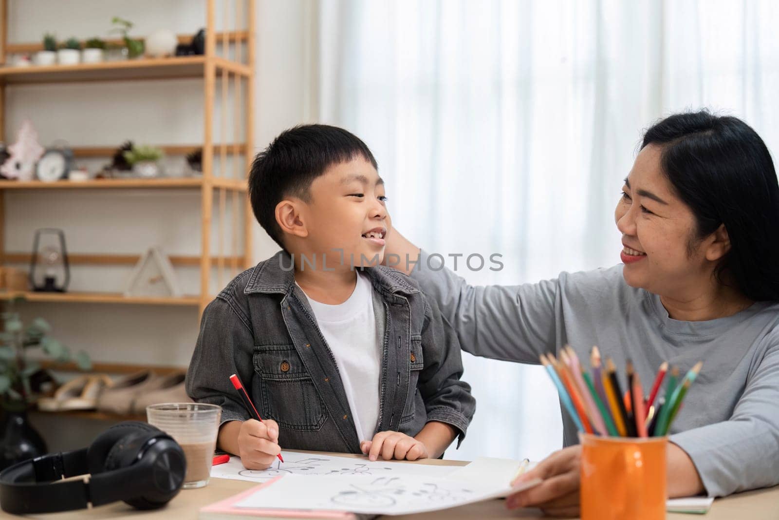 A mother and her son enjoy quality time together as they engage in drawing and art activities. The mother encourages her son, creating a supportive and fun environment for learning.