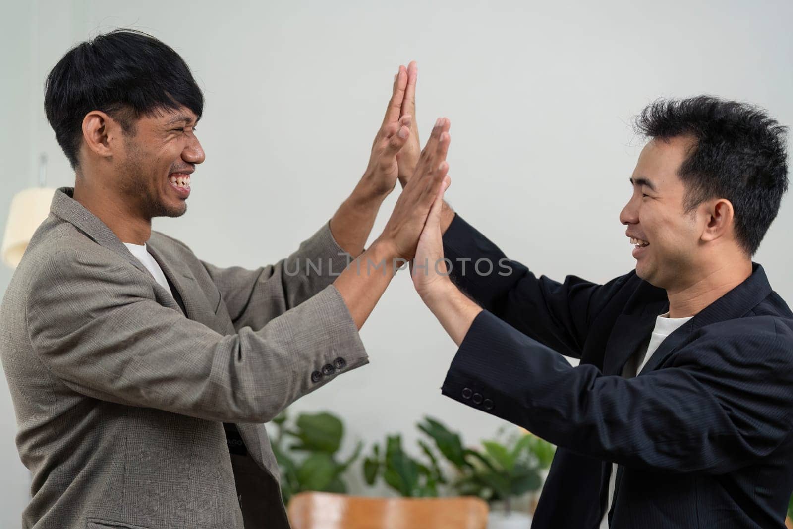 Two business partners express their excitement with a high-five, showcasing a positive work environment and camaraderie.