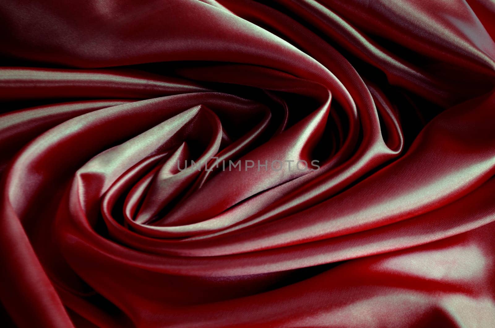 Top view of polished dark red silk cloth with silky sheen and beautiful natural draping. Suitable for design and wallpaper background.