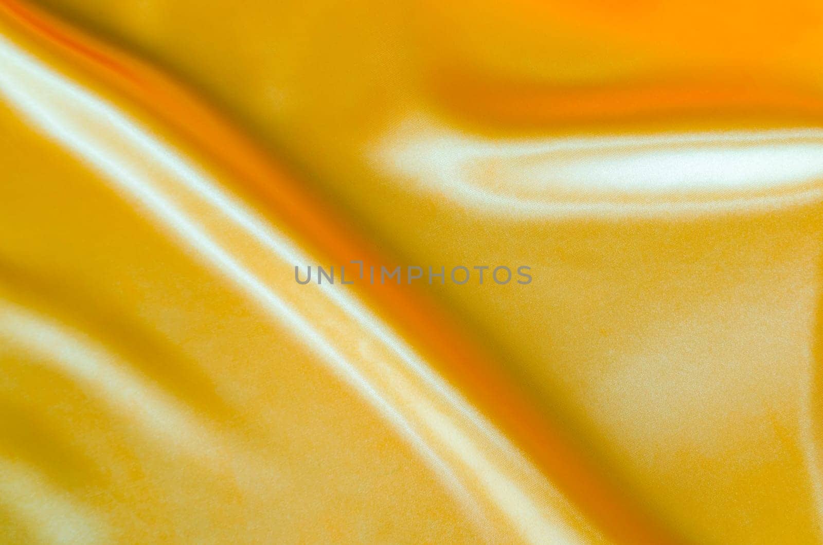 Top view of golden yellow silk with soft curves and vibrant reflective surface. Suitable for design and wallpaper background.