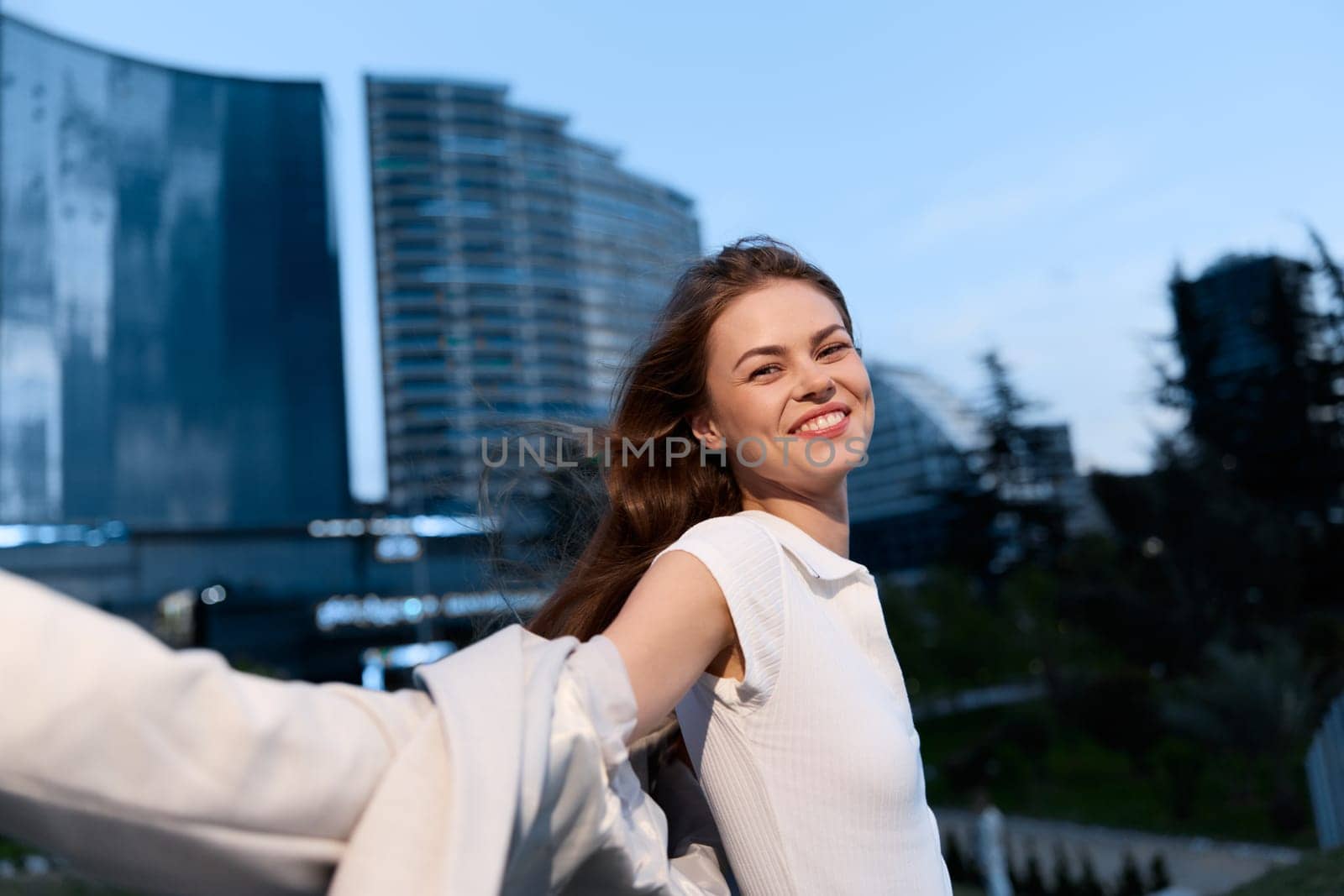 A confident businesswoman joyfully poses outdoors, surrounded by modern architecture, symbolizing empowerment and success in her professional journey.