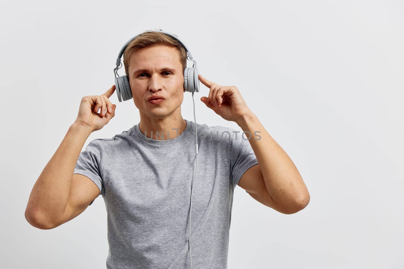 young caucasian man wearing headphones working with music listen and enjoy digital nomad lifestyle casual gray t-shirt isolated on plain white background technology and remote work concept