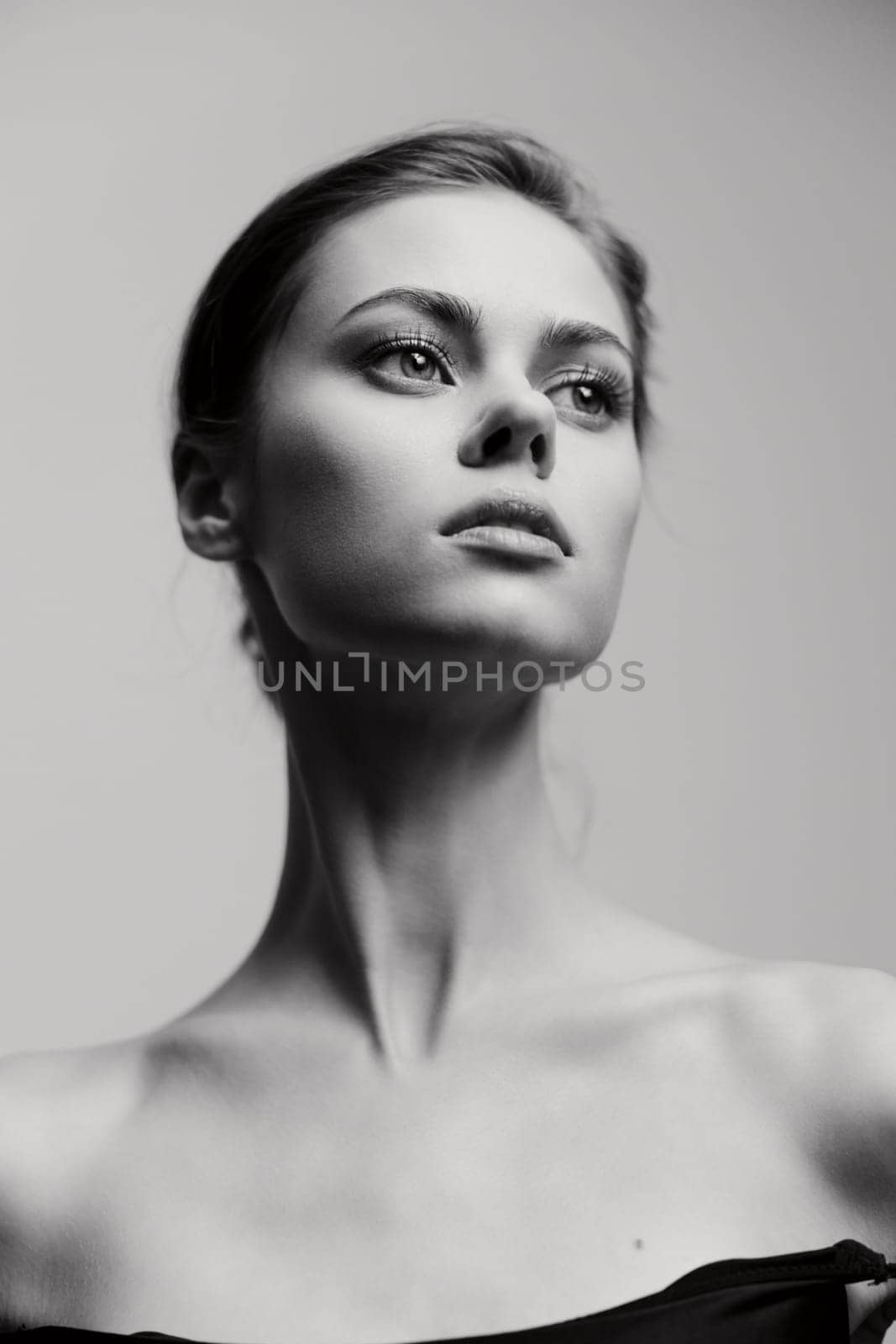 Striking black and white portrait of a young woman with an introspective gaze, highlighting her elegant features and minimalist style. Perfect for beauty and fashion themes.