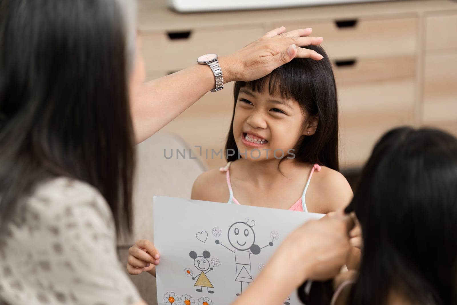 The grandmother supports her granddaughter by appreciating her artwork, fostering creativity and connection in a loving family environment.