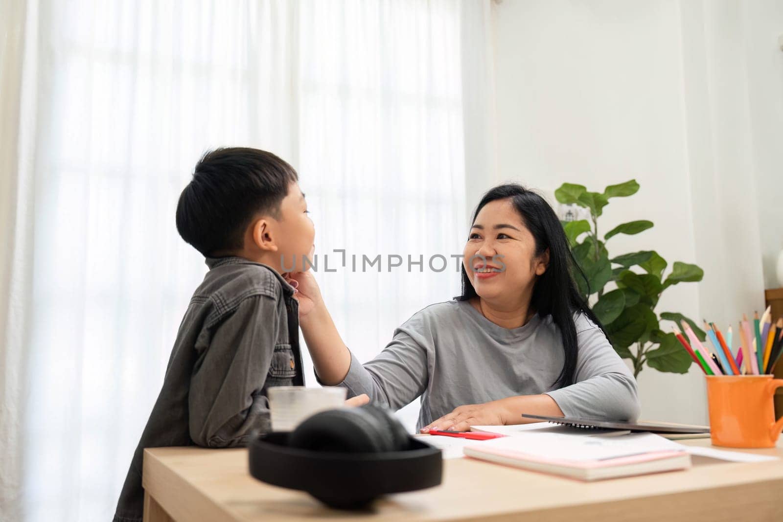 A mother and her son share a light-hearted moment while studying together. The mother provides encouragement and connection, enhancing their learning experience.