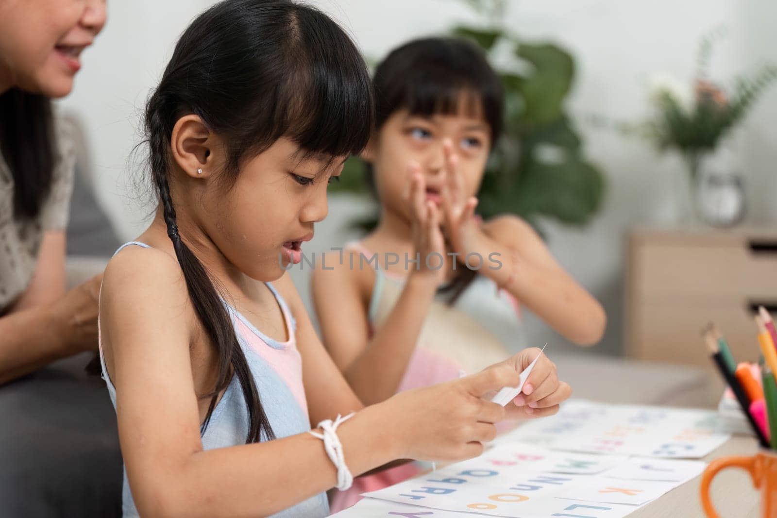 A grandmother engages her granddaughters in a fun learning activity, helping them identify letters while enjoying their time together.