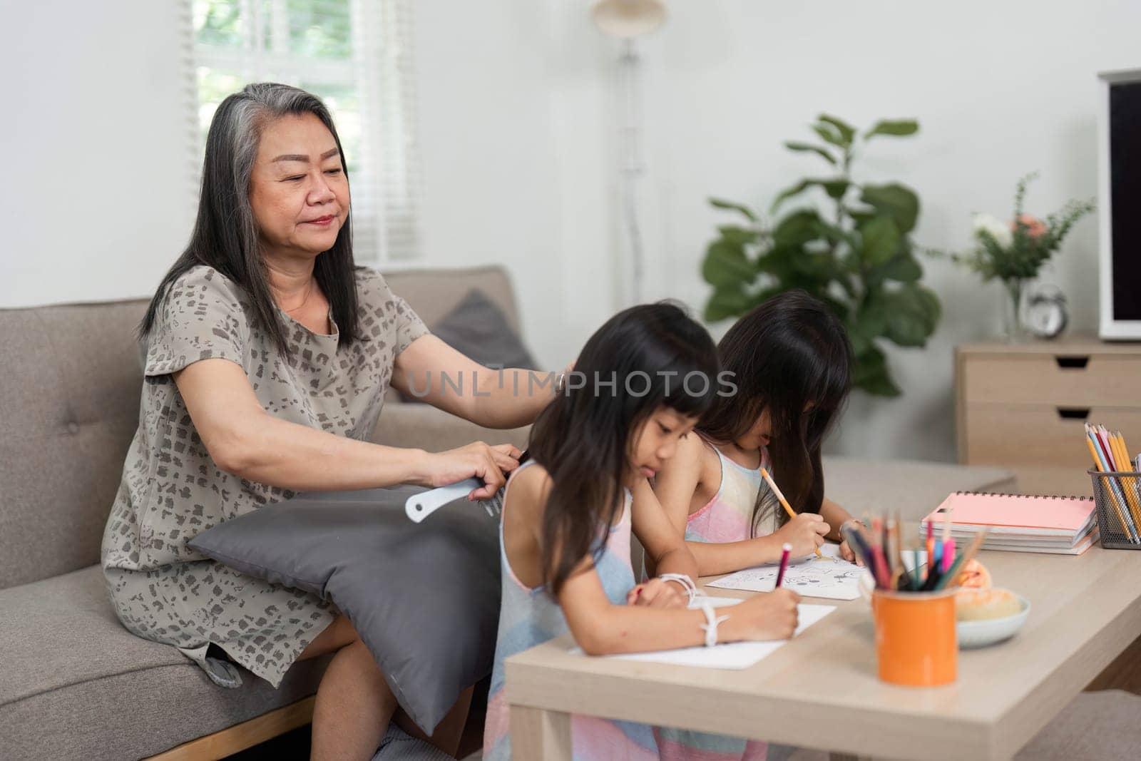 A warm moment captured as a grandmother assists her granddaughters in their artistic pursuits, promoting learning and creativity.
