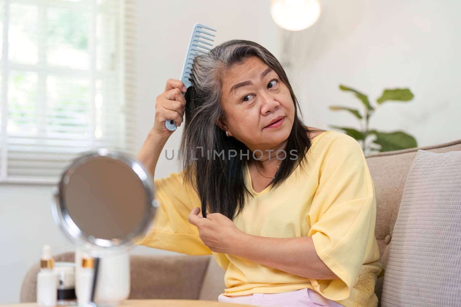 An older woman combs her hair, showcasing beauty and self-care routines that highlight the importance of grooming and personal appearance at any age.