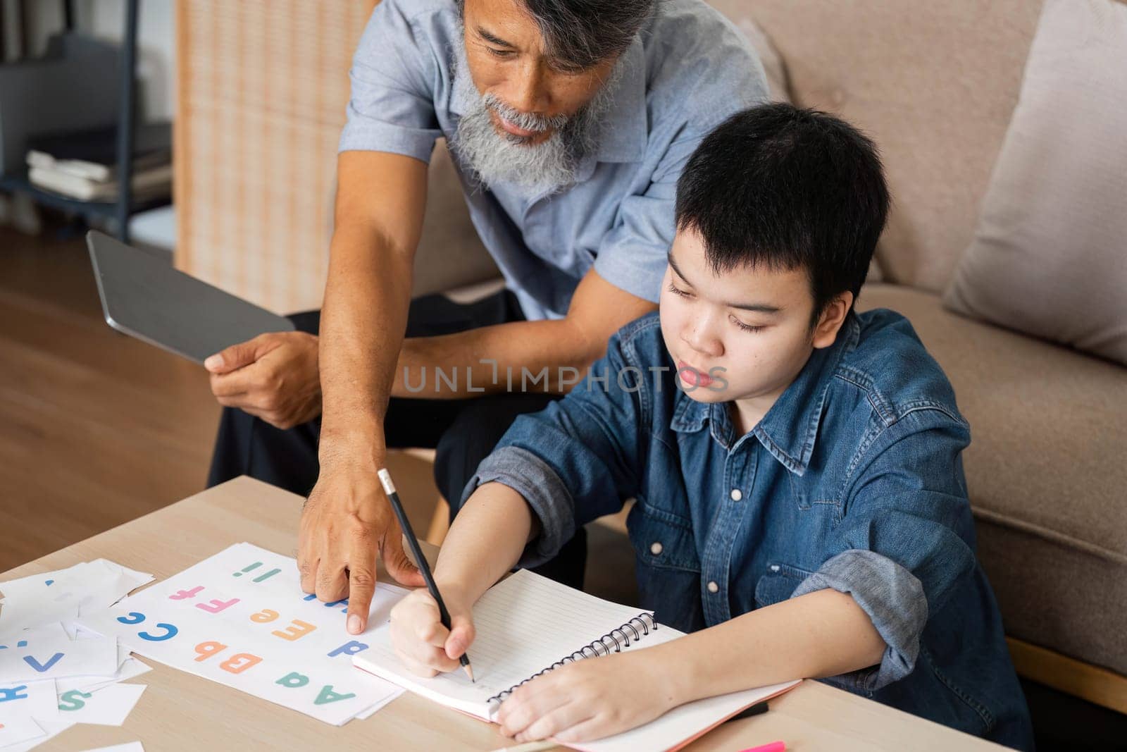 A caring grandfather helps his grandchild with learning letters and numbers, showcasing a warm and supportive educational environment.