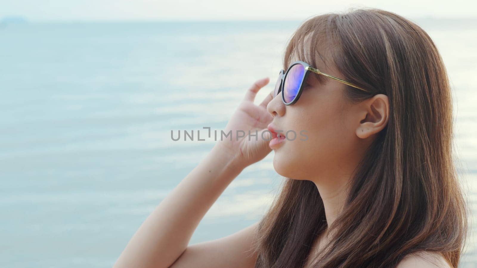 Beautiful Asian woman wearing sunglasses at tropical paradise beach and smiling, Happy female in bikini swimsuit having fun eyewear in holidays summer vacation travel