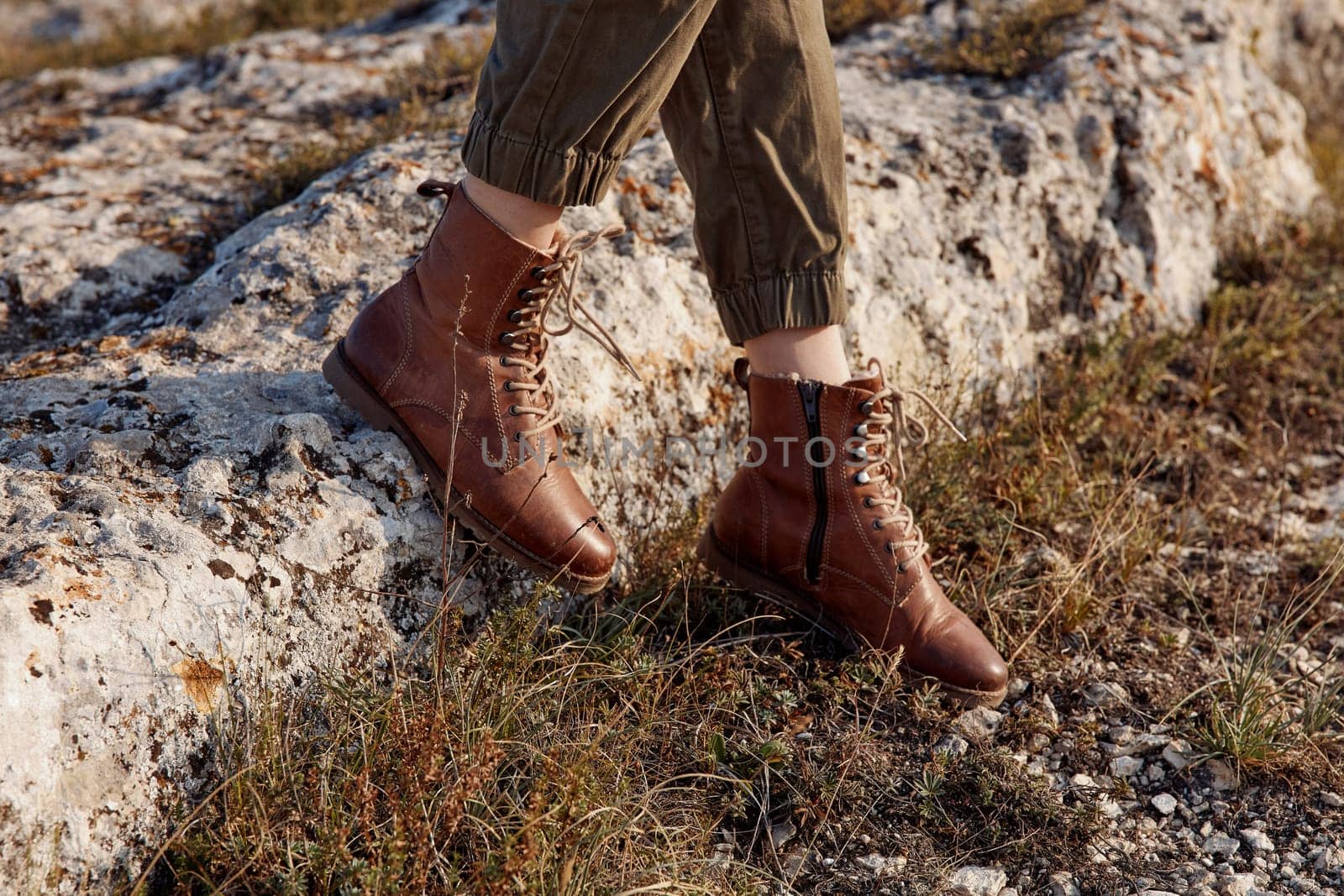 Woman in brown leather boots standing on rock in field under sunny sky travel adventure beauty nature landscape artistic beauty portrait concept