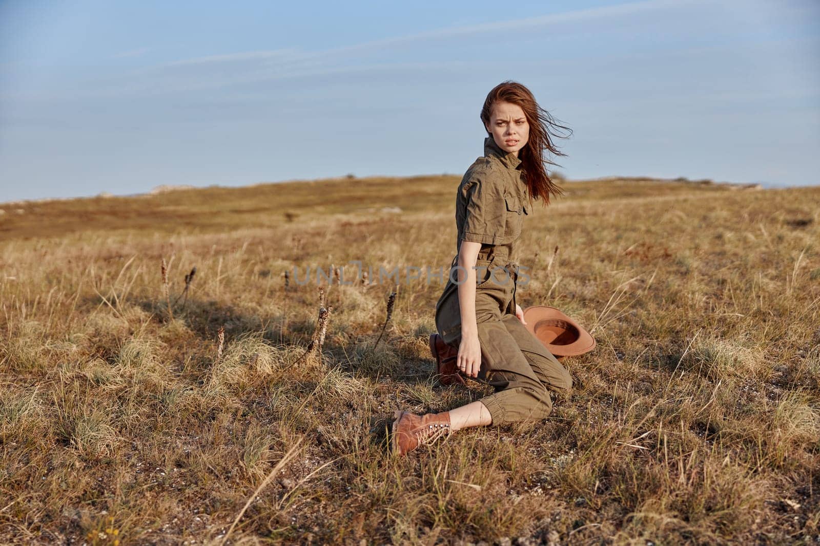 Woman sitting in grass field with hat, enjoying nature and relaxing moment in the outdoors