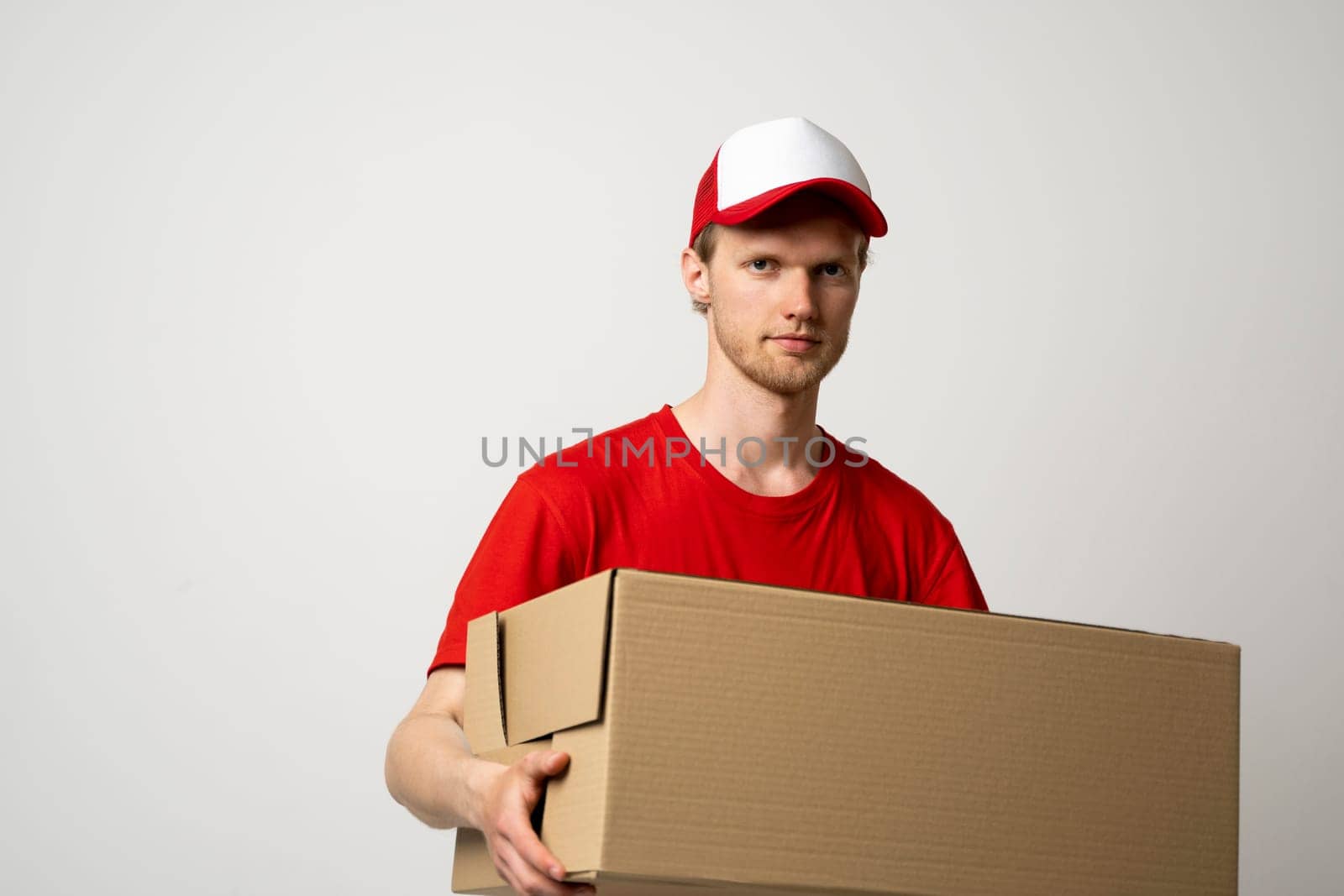Courier in red t-shirt holding a cardboard box. Express service for shipping packages, food, and goods