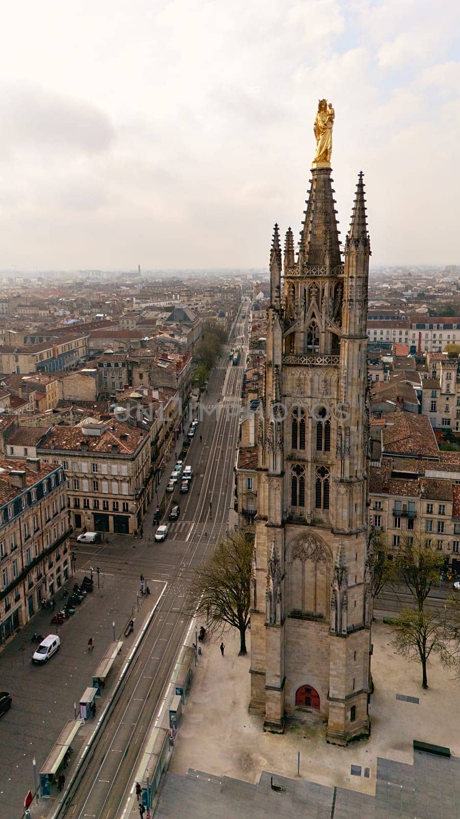 Close up view of the Pey Berland Tower in Bordeaux France with golden statue and panoramic cityscape under cloudy sky