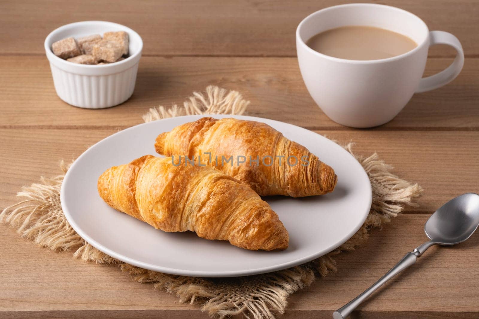 Freshly baked croissants served with a hot cup of coffee on a wooden table in a cozy setting.