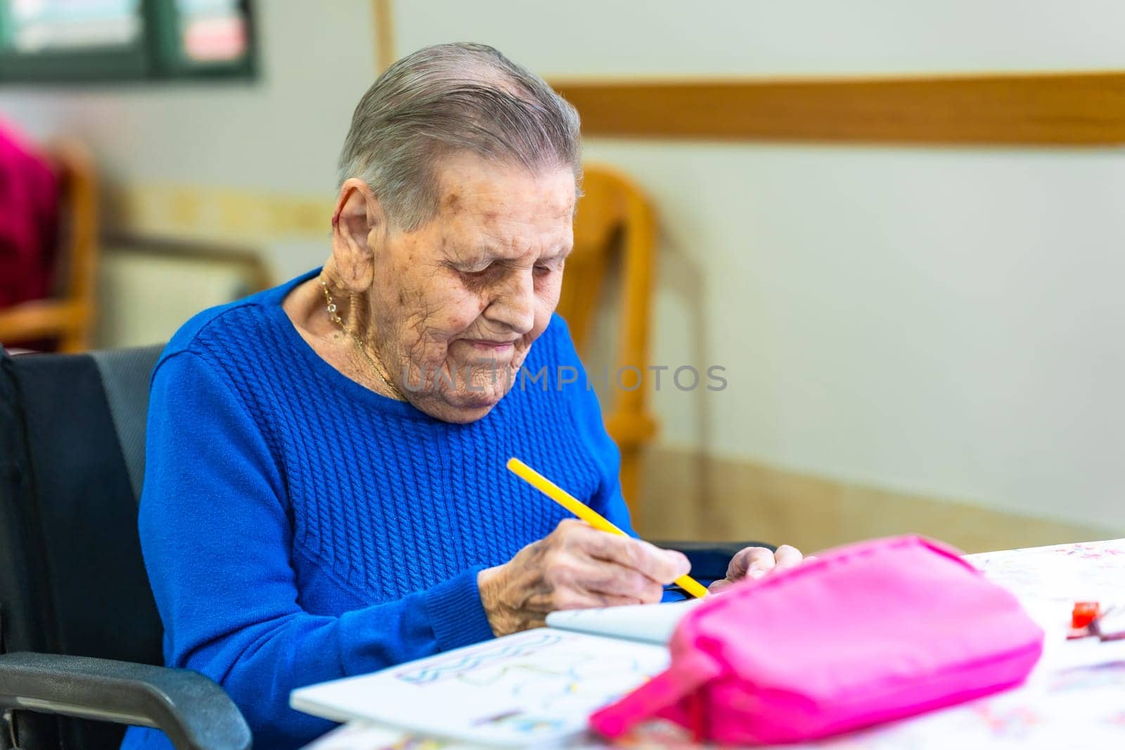 Senior woman enjoying creative time, drawing with colored pencils in a nursing home, showcasing a fulfilling and engaging activity