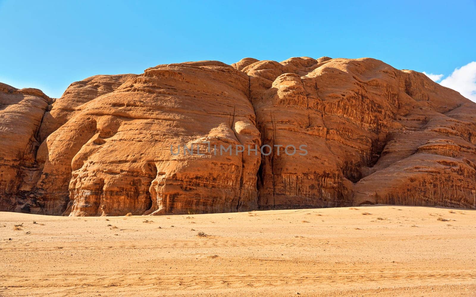 Rocky massifs on red sand desert, bright blue sky in background - typical scenery in Wadi Rum, Jordan