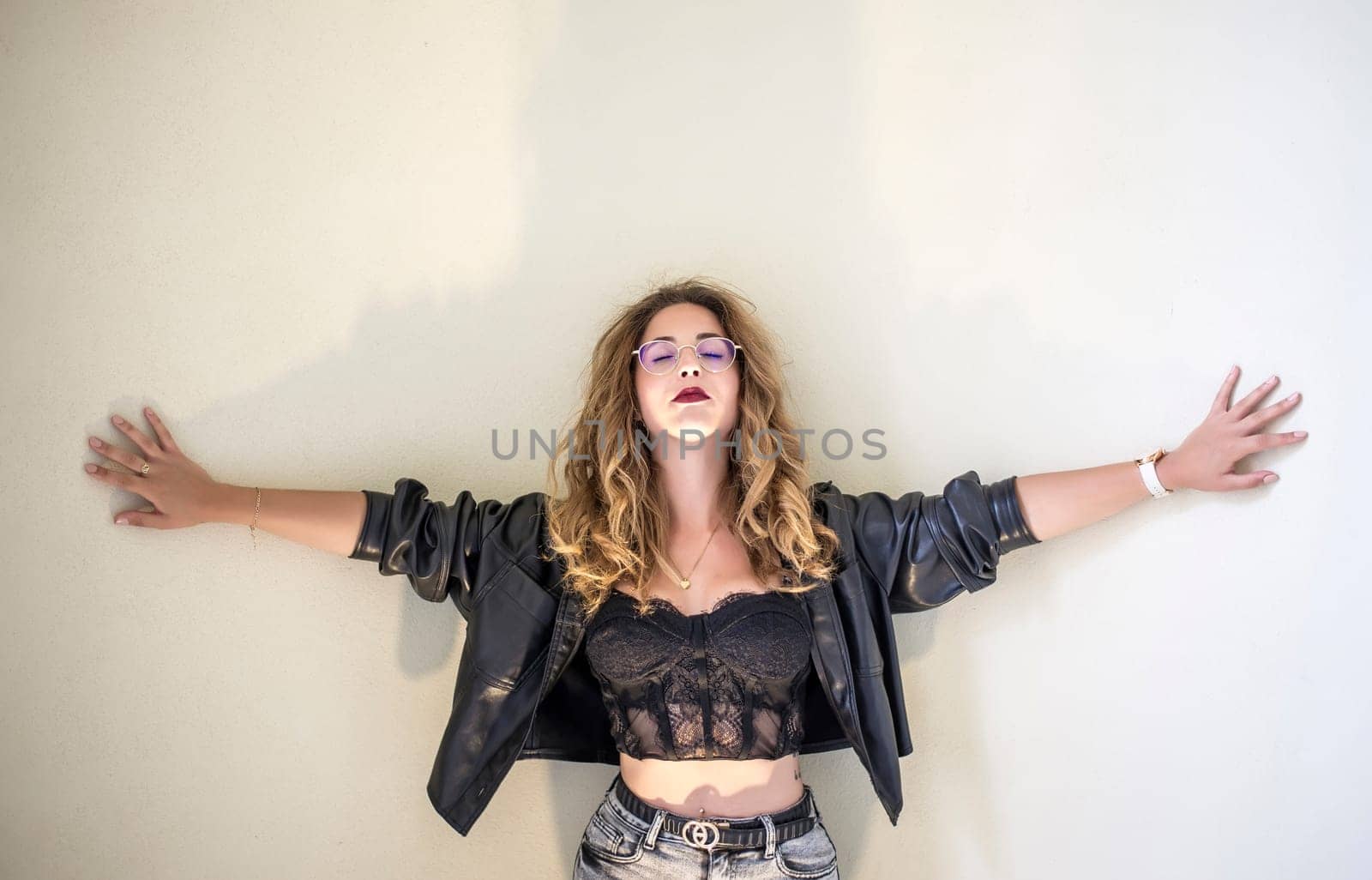 thoughtful young woman stands in front of a wall