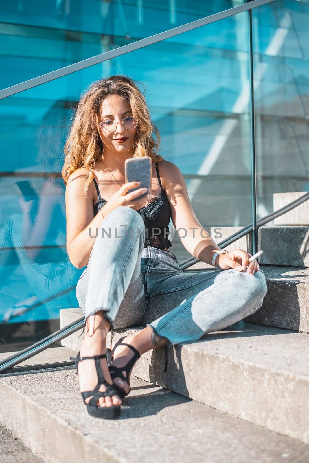 relaxed young woman with smartphone and cigarette in the city