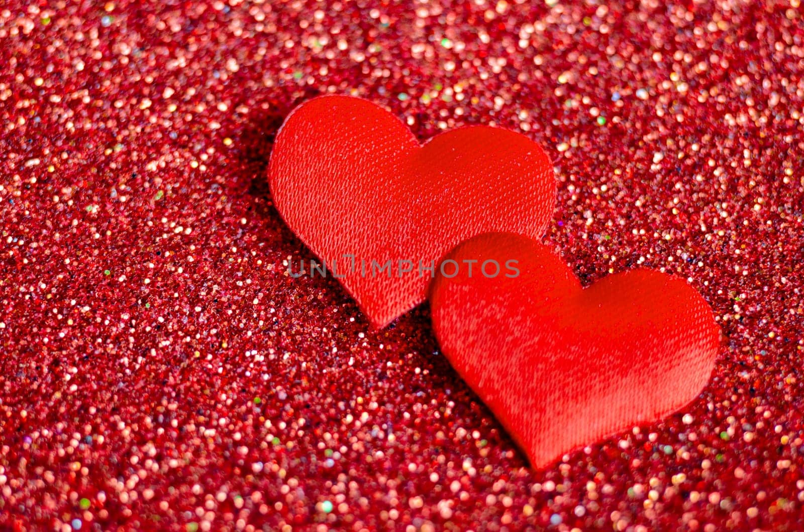 Top view of tiny red hearts on sparkle red background with customizable space for text or wishes.