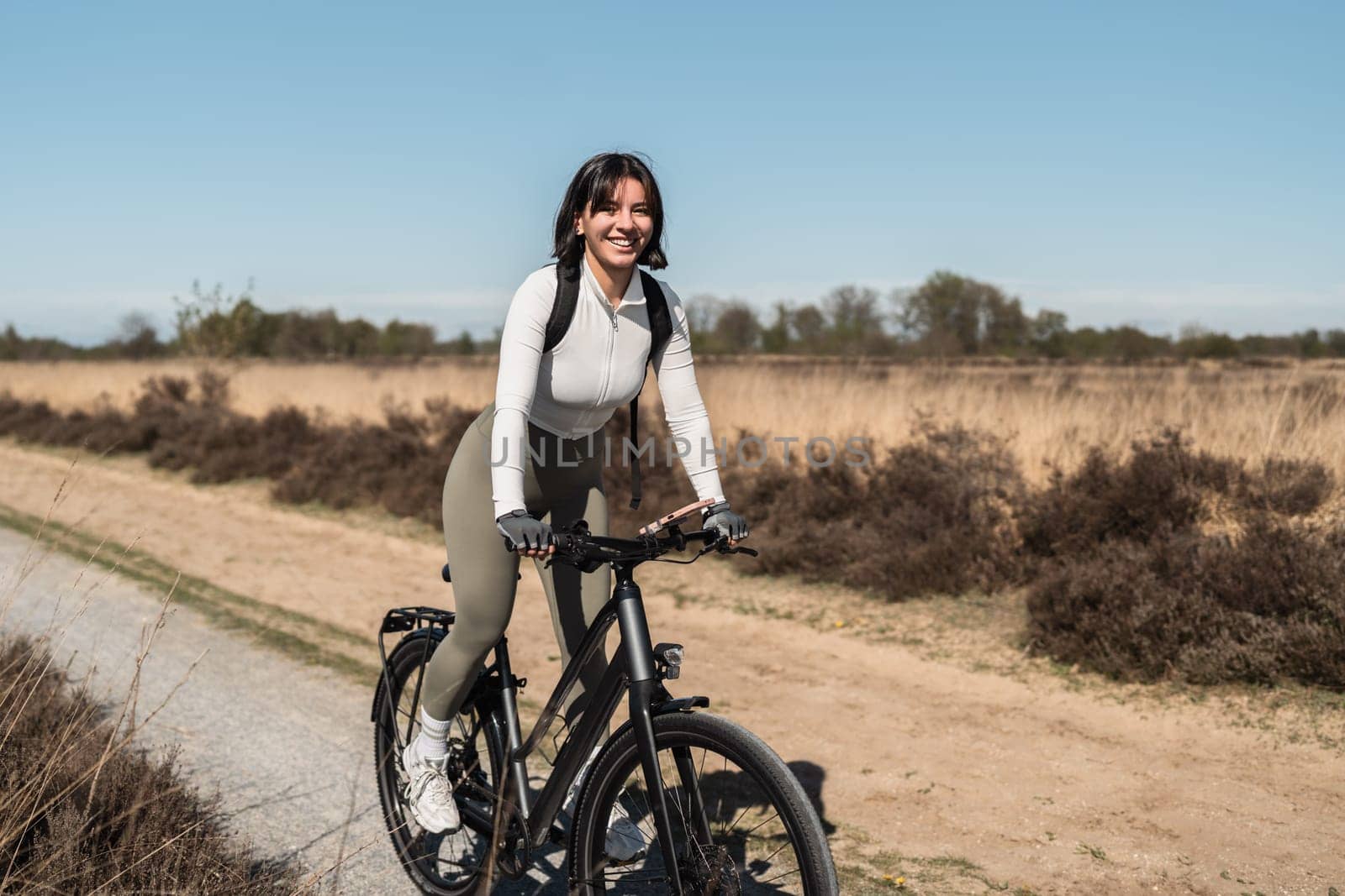 Golden hour ride with a smiling woman in light attire cruising on her bike, blending active living with carefree outdoor vibes.
