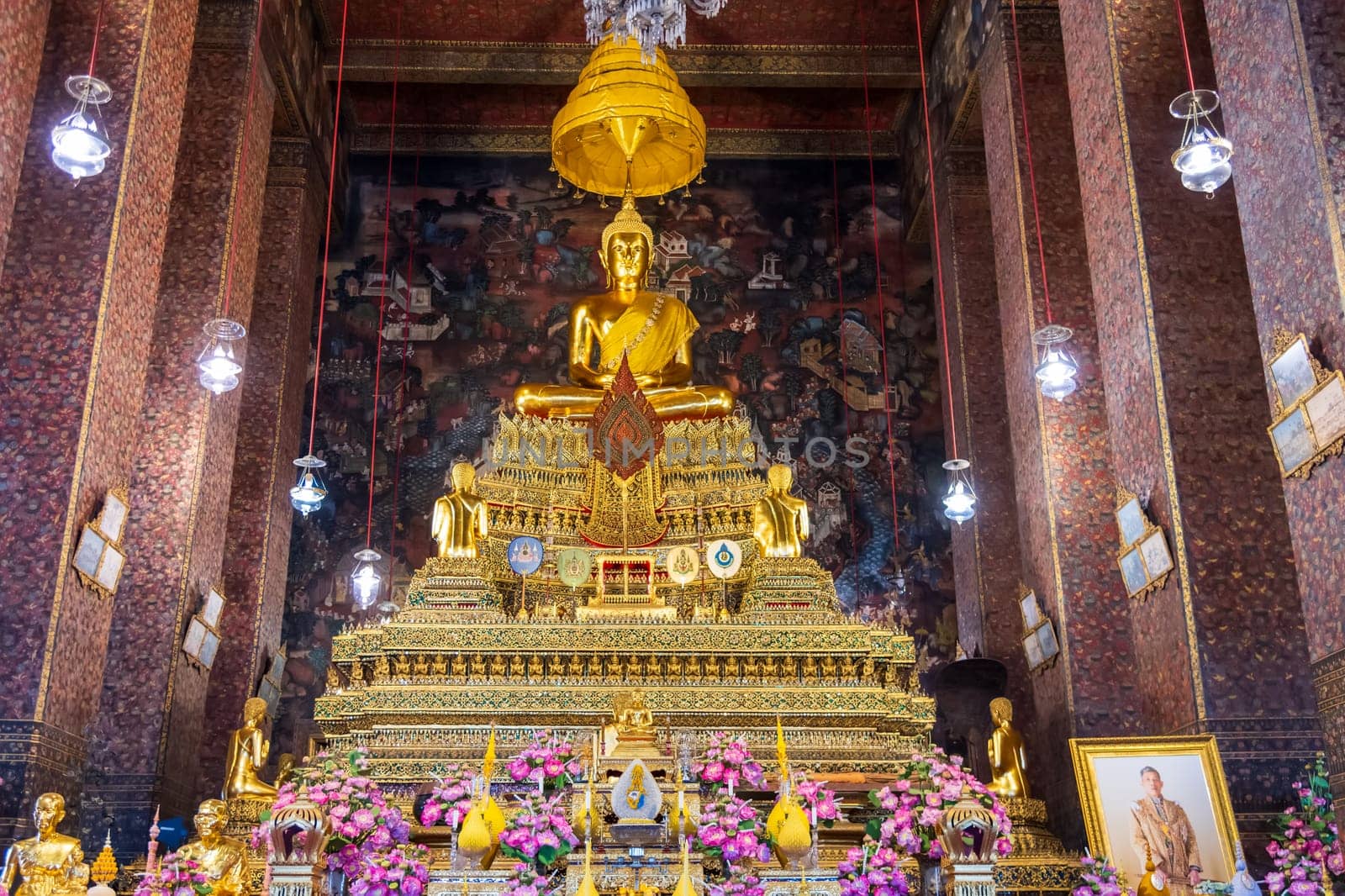 In a peaceful temple, a magnificent golden Buddha statue is surrounded by vibrant, colorful flowers