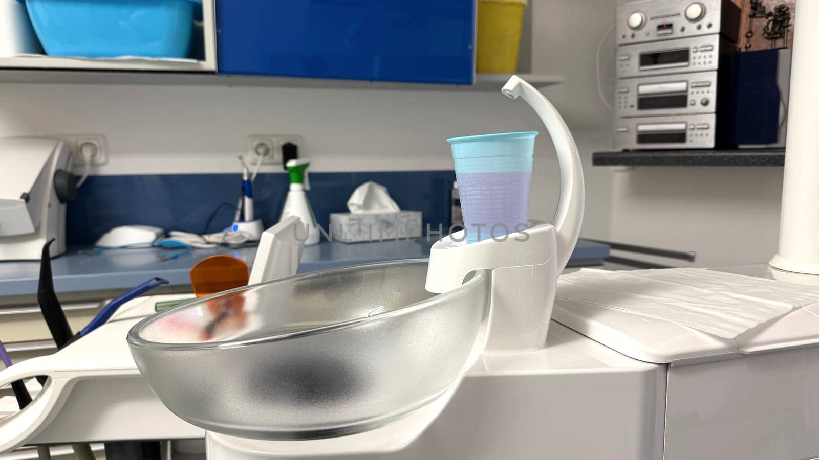 Medical equipment includes a transparent bowl and a blue cup placed on a countertop in a clinical environment highlighting healthcare tools and hygiene