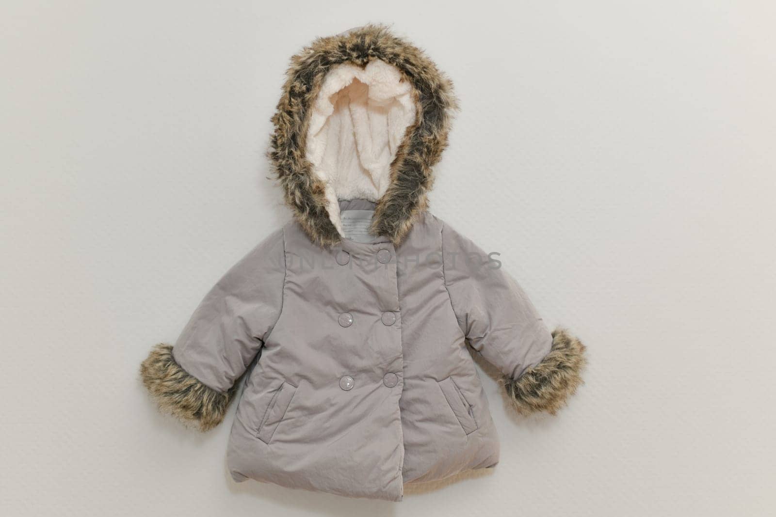 Grey-lilac colored fur jacket for girl hanging on hanger on white background