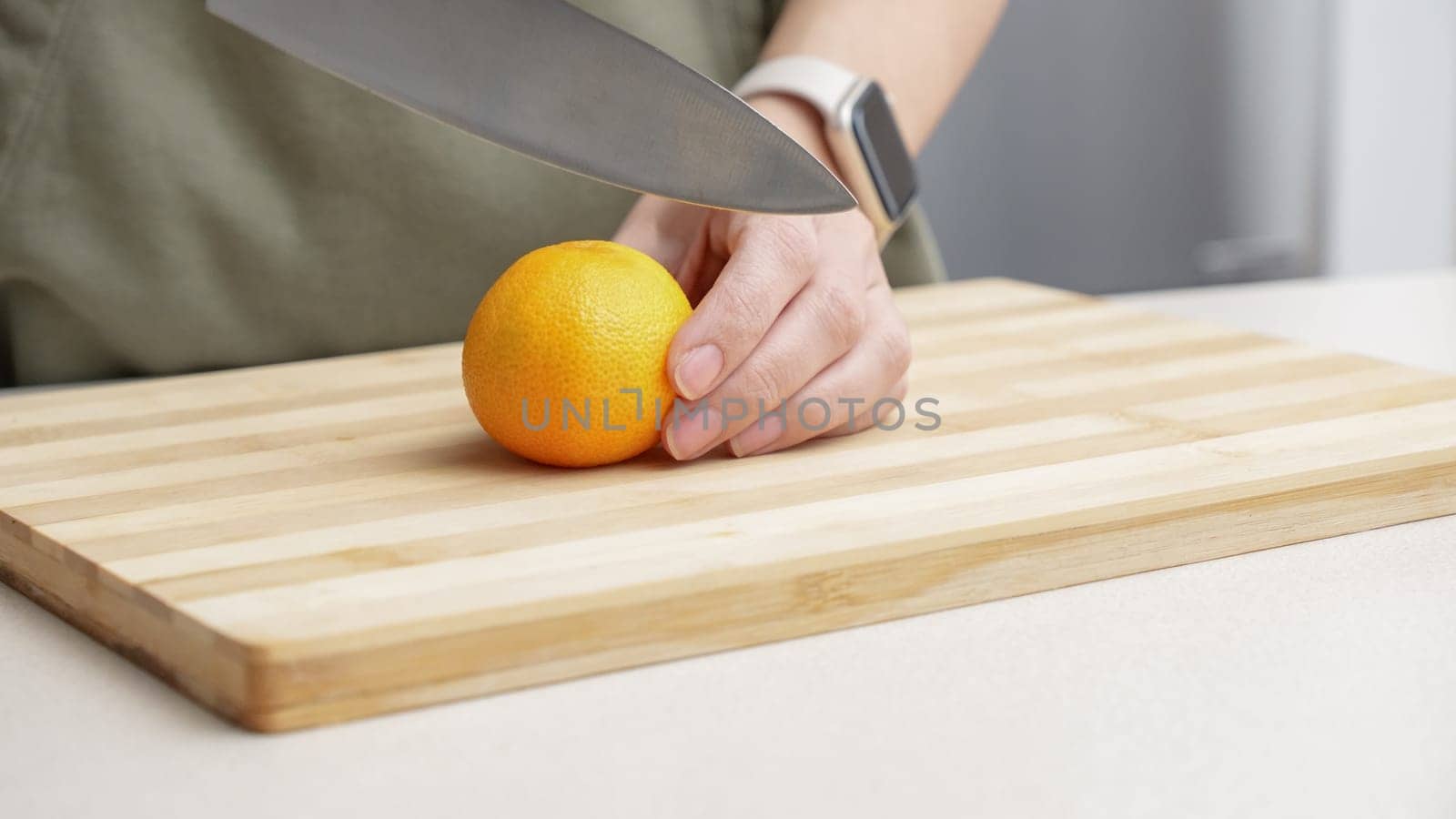 Hands cutting orange tangerines on the cutting board on table, lots of juicy fresh fruits for cooking.