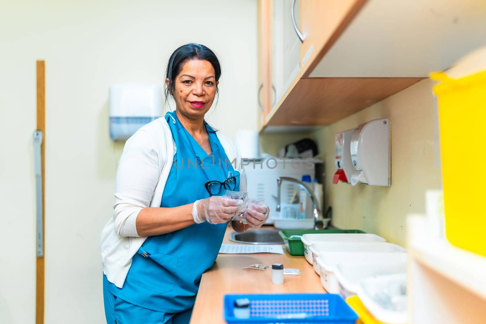 Confident mature female nurse wearing gloves preparing medication in a nursing home treatment room