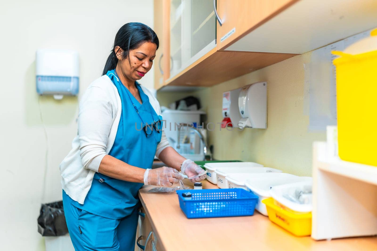 Nurse wearing gloves preparing medication for residents in the pharmacy of a nursing home