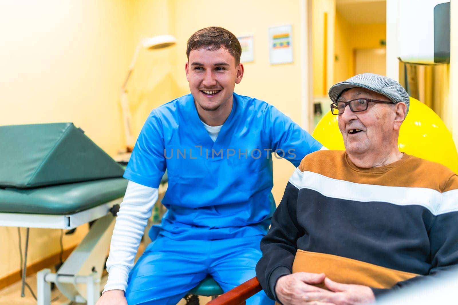 Young doctor smiling and talking with elderly patient in nursing home, showing care and empathy