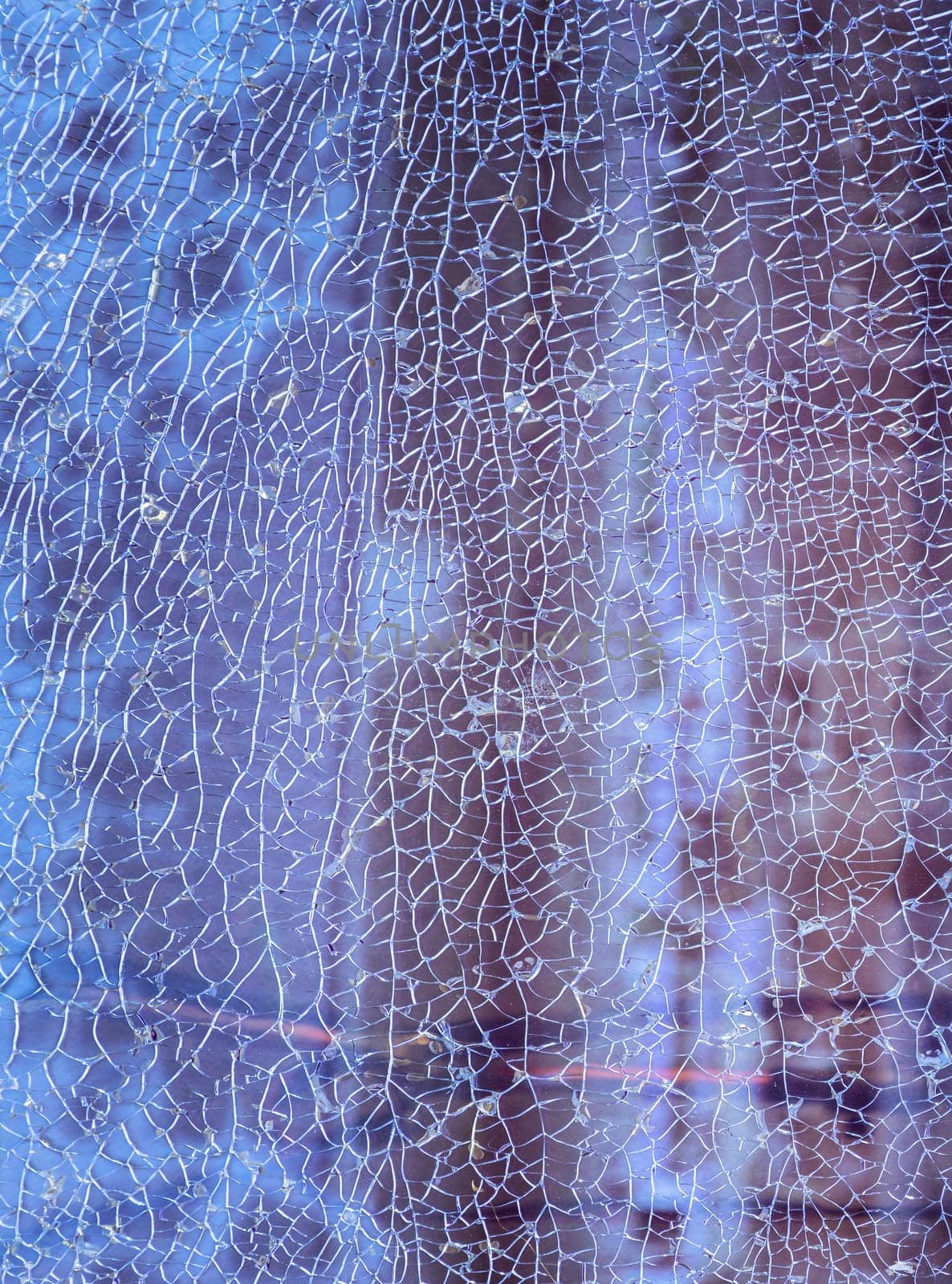 Newcastle, UK - Apr 11, 2025 - Cracks on the glass surface background. Texture of broken tempered glass pane too many small irregular shape pieces holding together. Detail of cracked broken glass cracked by impact, use it as your Wallpaper, Poster and Copy space, Selective focus.