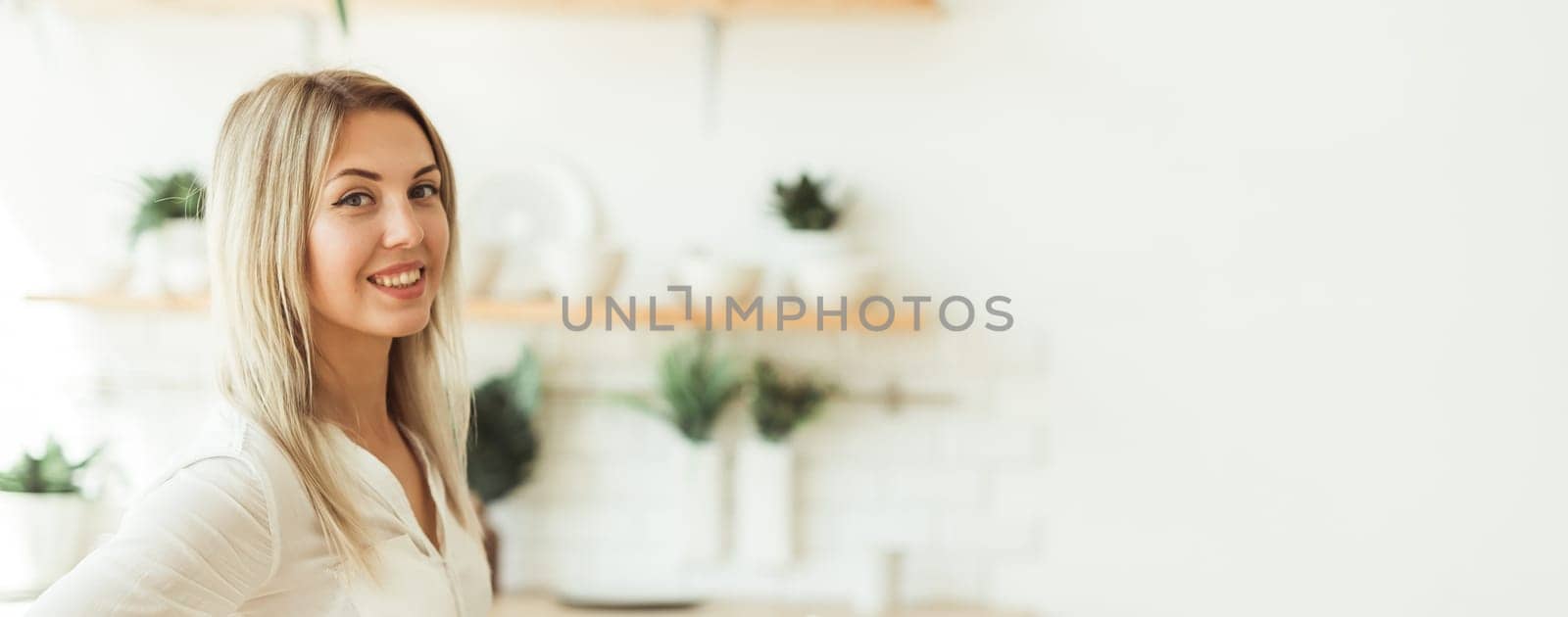 Portrait of a smiling woman standing at home. Positive attitude and modern lifestyle concept. Banner with copy space.