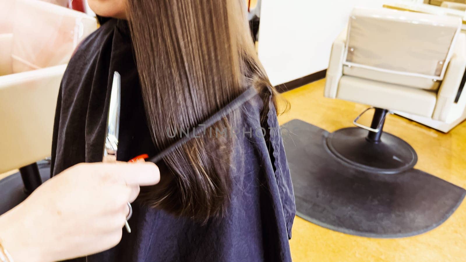 Gentle hands maneuver a hair dryer through a young girl's newly cut hair, showcasing the drying process after a meticulous trim. The warmth of the dryer breathes life into her locks, as they transform from damp to styled with care and expertise.