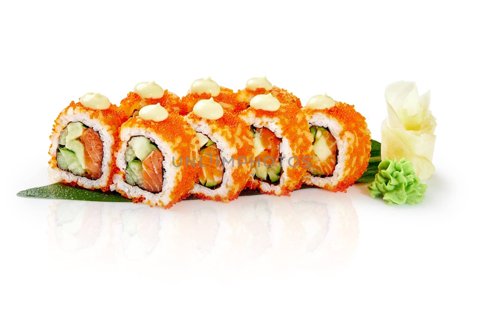 Delicious california uramaki sushi rolls with red tobiko caviar, salmon, avocado, cucumber and mayonnaise, resting on a bamboo leaf with wasabi and gari