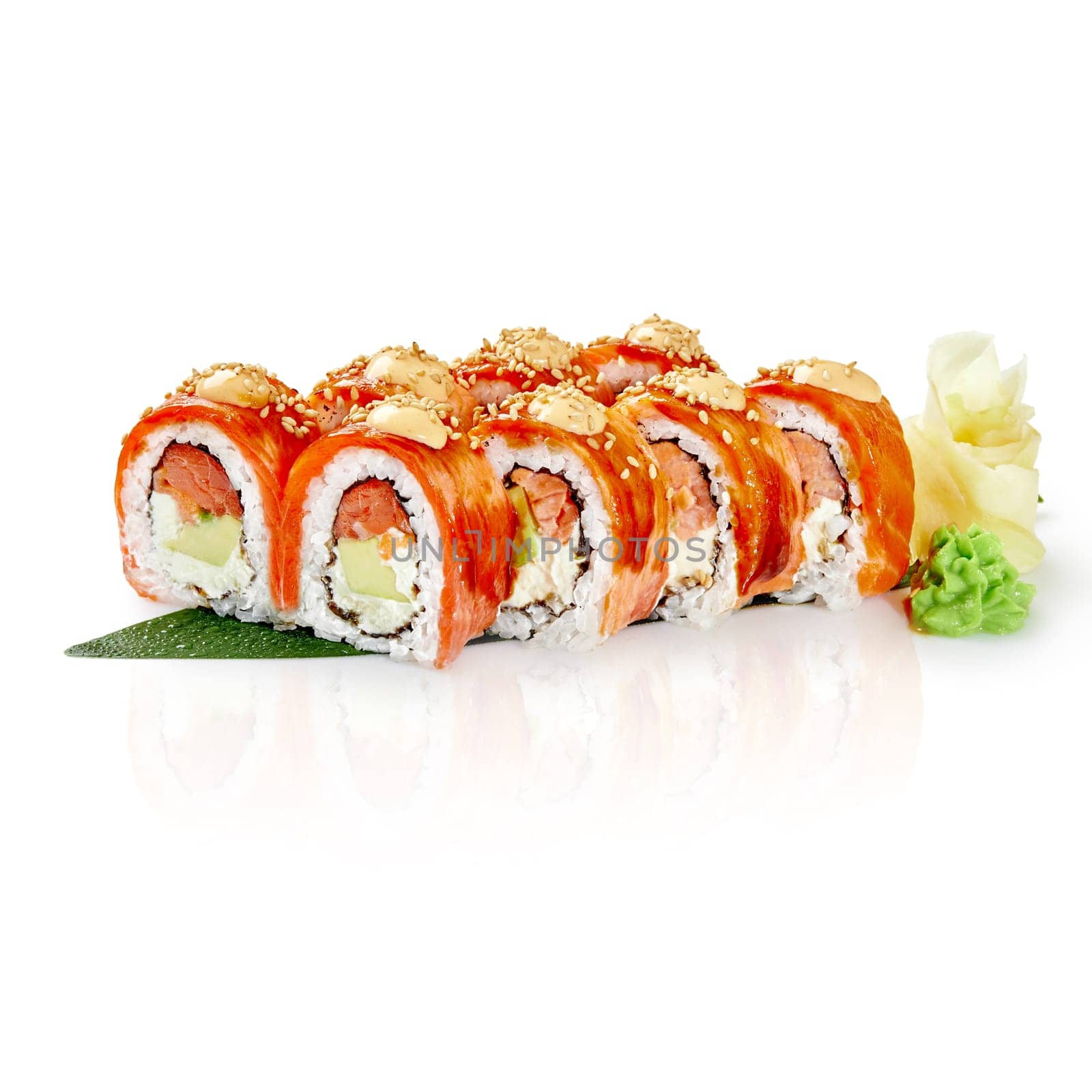Delicious philadelphia uramaki sushi rolls decorated with sesame and spicy sauce lying on green bamboo leaf