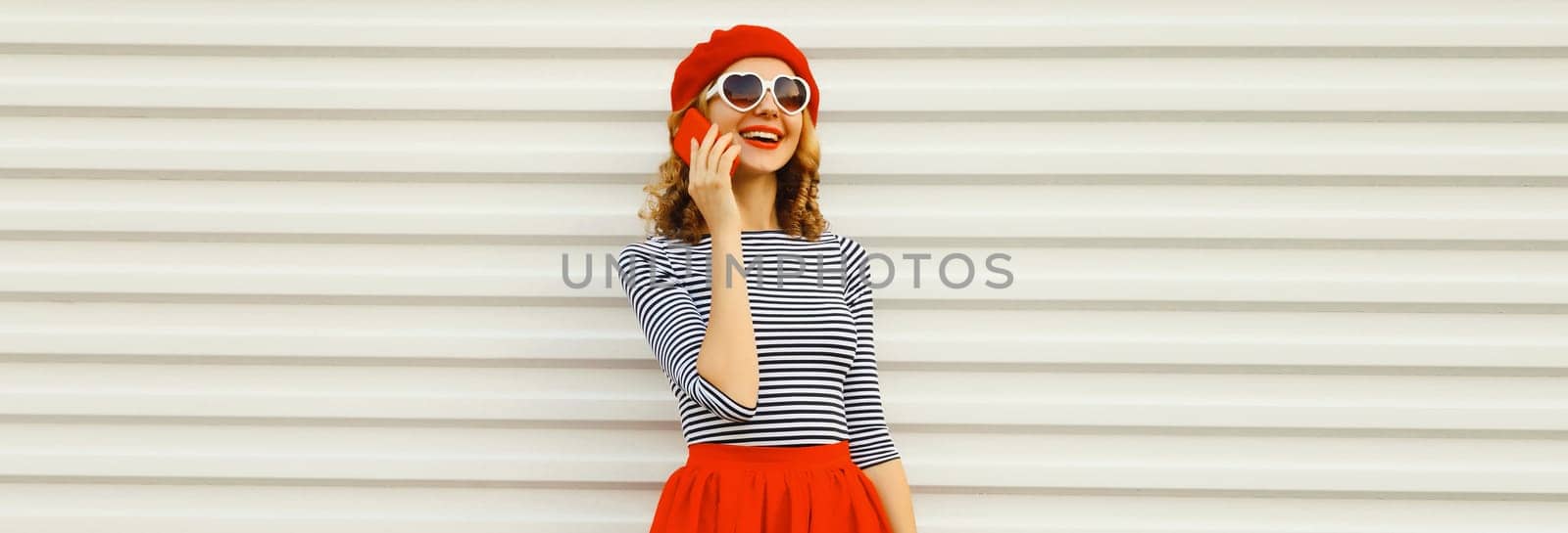 Beautiful happy smiling young woman calling on phone, stylish girl talking on the smartphone in red skirt, french beret hat on white background