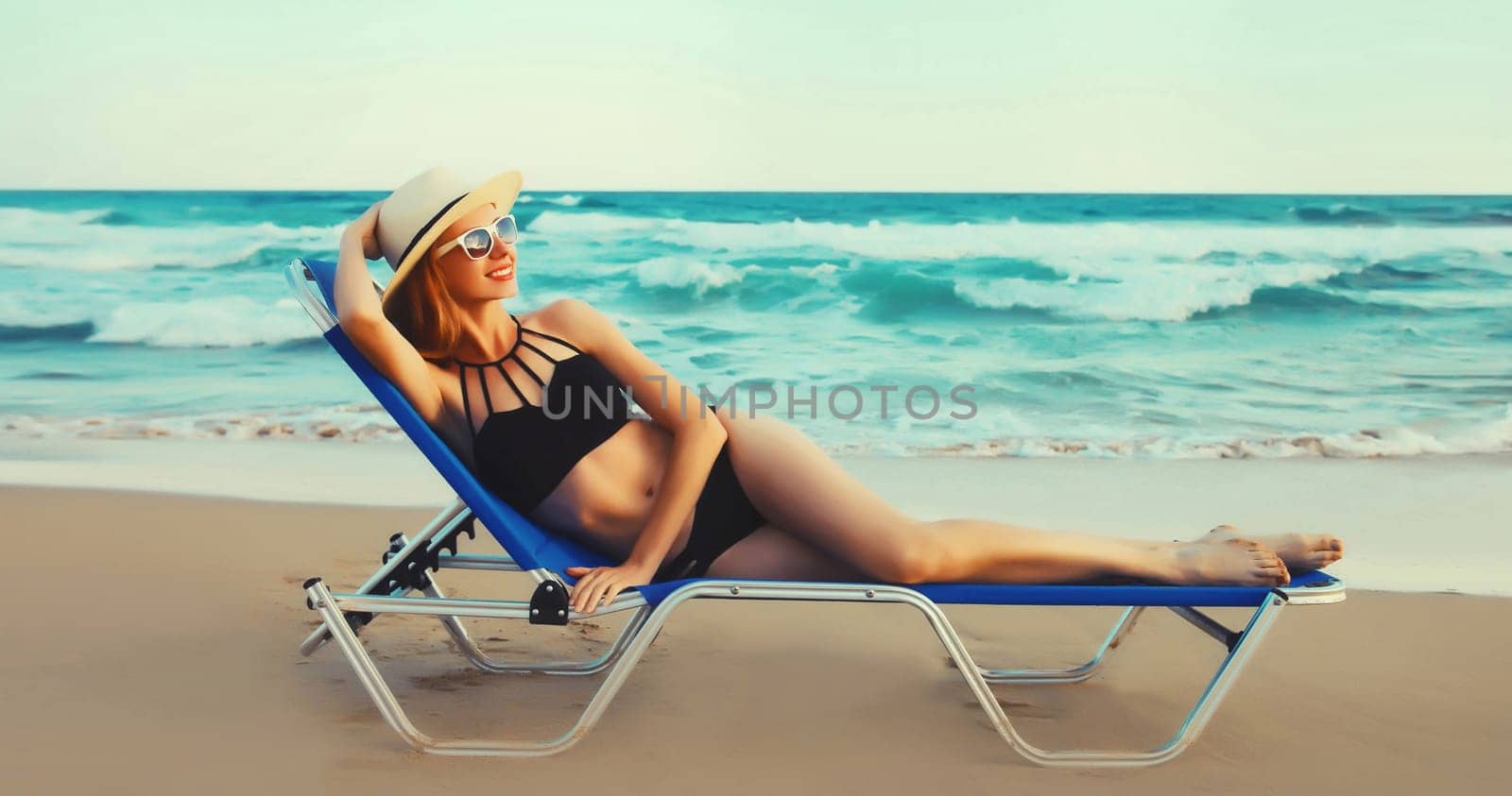 Summer vacation, happy relaxing young woman lying on deckchair on the beach on sea background