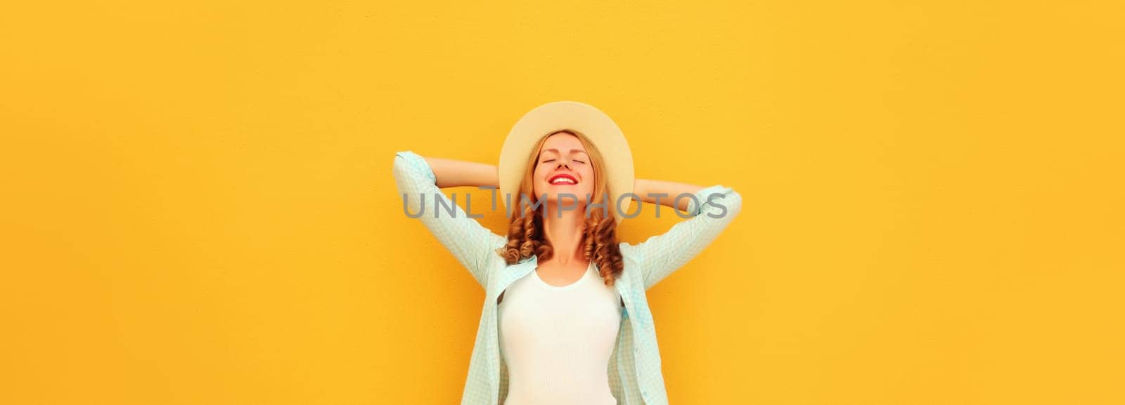 Summer vacation, fashion, lifestyle. Happy joyful relaxed young woman enjoying sunny warm day in tourist straw hat, standing on bright yellow background