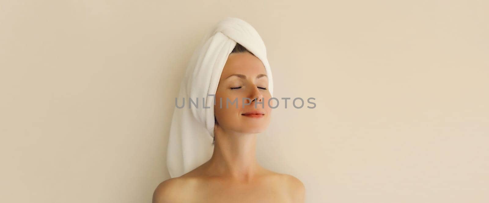 Natural beauty portrait of happy young caucasian woman enjoying her clean skin drying wet hair with white bath towel on her head