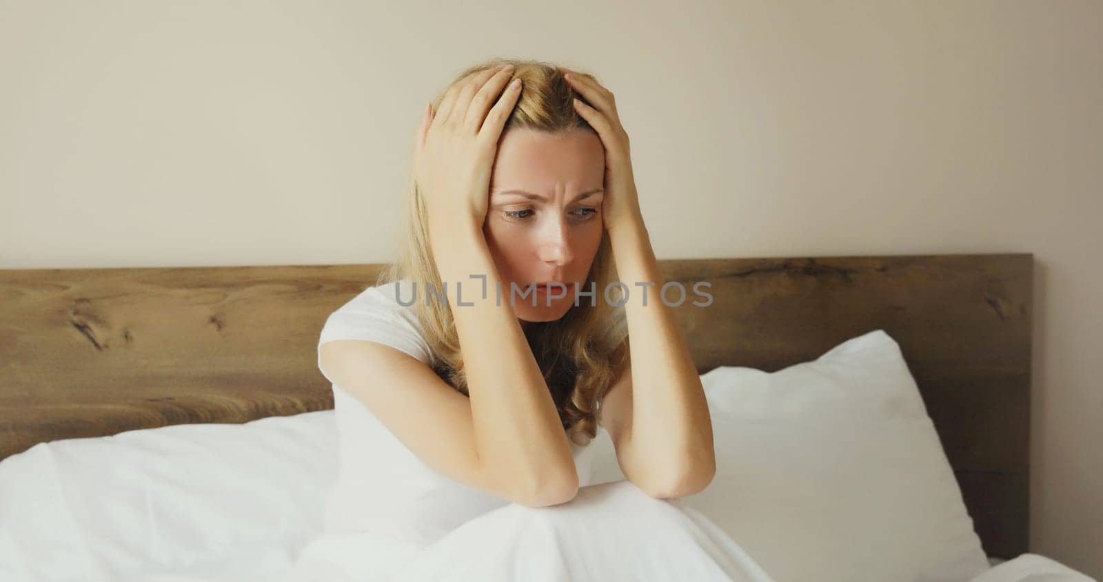 Exhausted tired woman touching head, suffering from headache, stress, fatigue, temples pain, migraine, loud noise, tension lying on the bed in bedroom at home